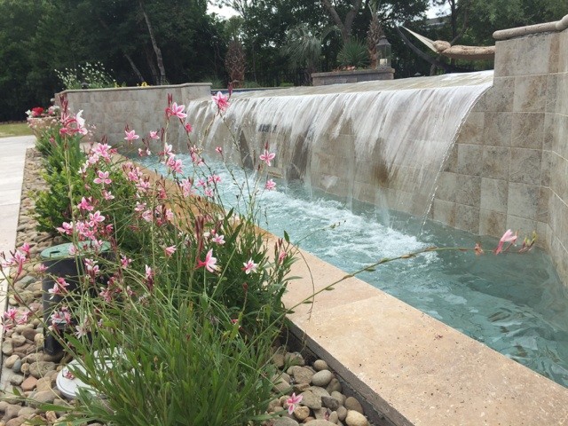 Ispirazione per una grande piscina stile marinaro personalizzata dietro casa con fontane e pavimentazioni in pietra naturale