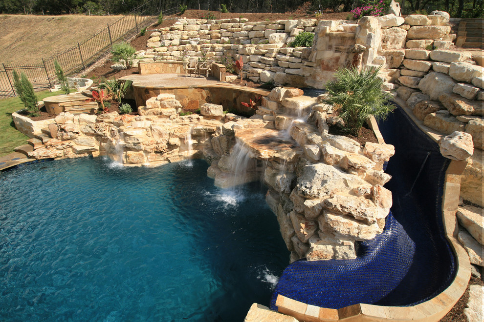 Example of a large trendy backyard custom-shaped natural pool fountain design in Austin with decking