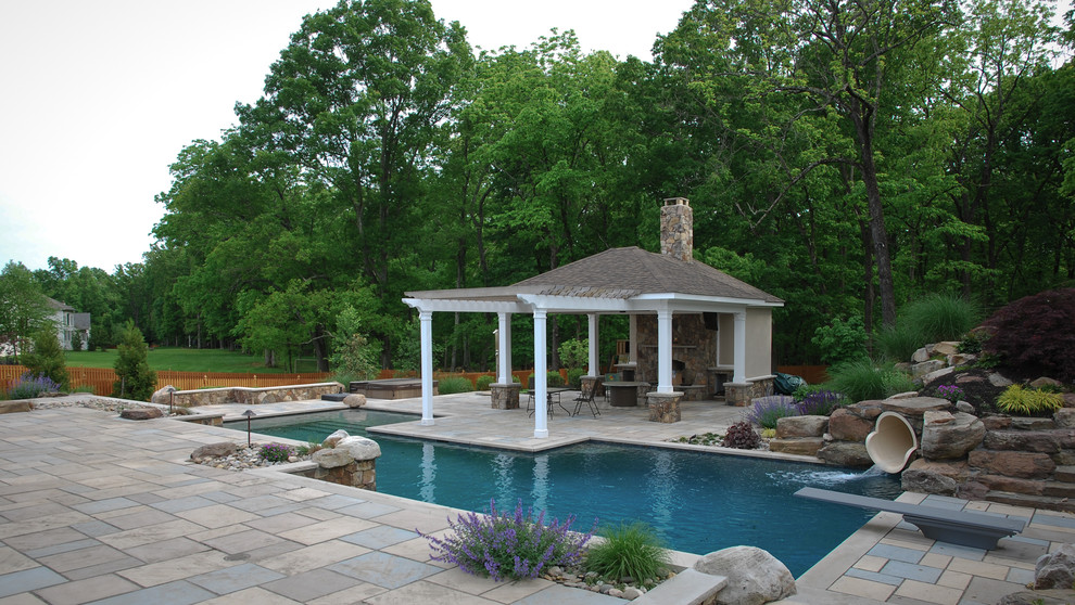 Foto de piscina con tobogán natural clásica de tamaño medio a medida en patio trasero con adoquines de hormigón