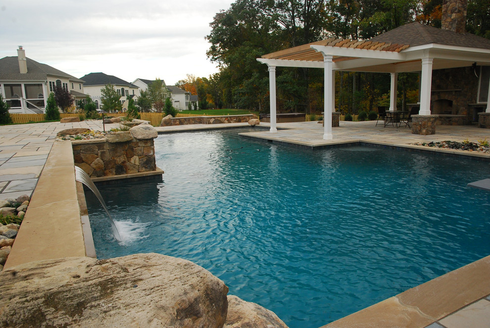Diseño de piscina con tobogán natural tradicional de tamaño medio a medida en patio trasero con adoquines de hormigón