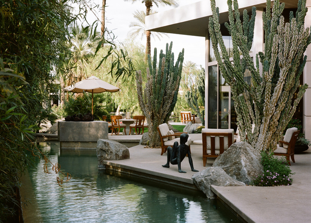 Immagine di una piscina monocorsia etnica personalizzata di medie dimensioni e dietro casa con lastre di cemento