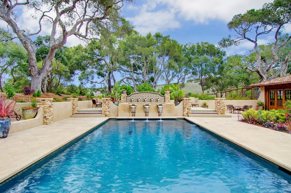 Foto di una grande piscina monocorsia mediterranea rettangolare dietro casa con una vasca idromassaggio e pavimentazioni in pietra naturale