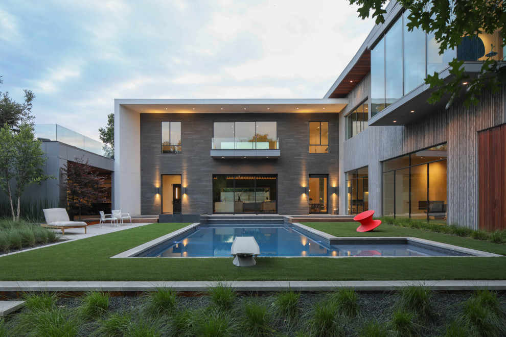 Immagine di una grande piscina design a "L" dietro casa con una vasca idromassaggio