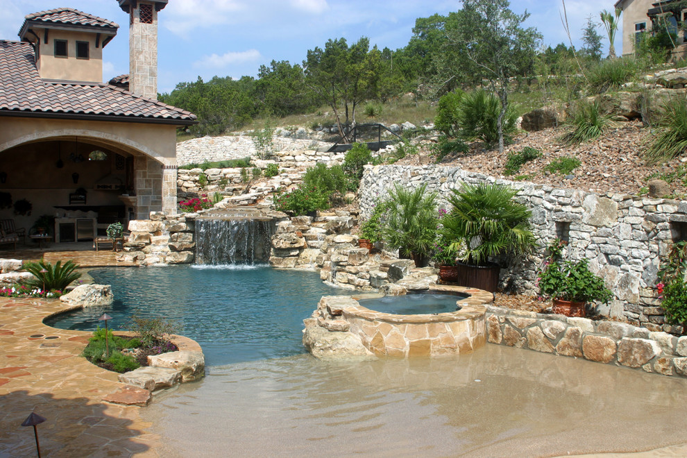 Réalisation d'une grande piscine arrière marine sur mesure avec des pavés en pierre naturelle et un bain bouillonnant.