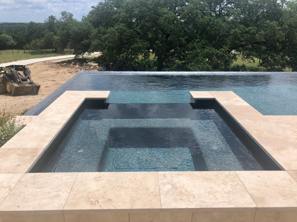 Свежая идея для дизайна: огромный прямоугольный бассейн-инфинити на заднем дворе в стиле модернизм с джакузи и покрытием из каменной брусчатки - отличное фото интерьера