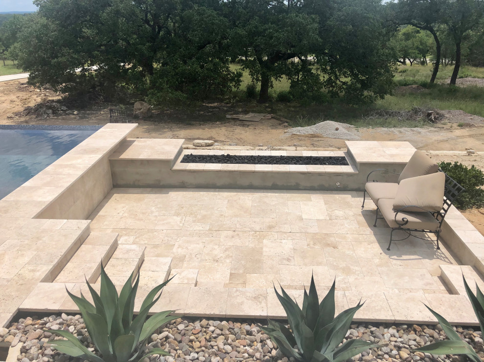 Réalisation d'une très grande piscine à débordement et arrière minimaliste rectangle avec un bain bouillonnant et des pavés en pierre naturelle.