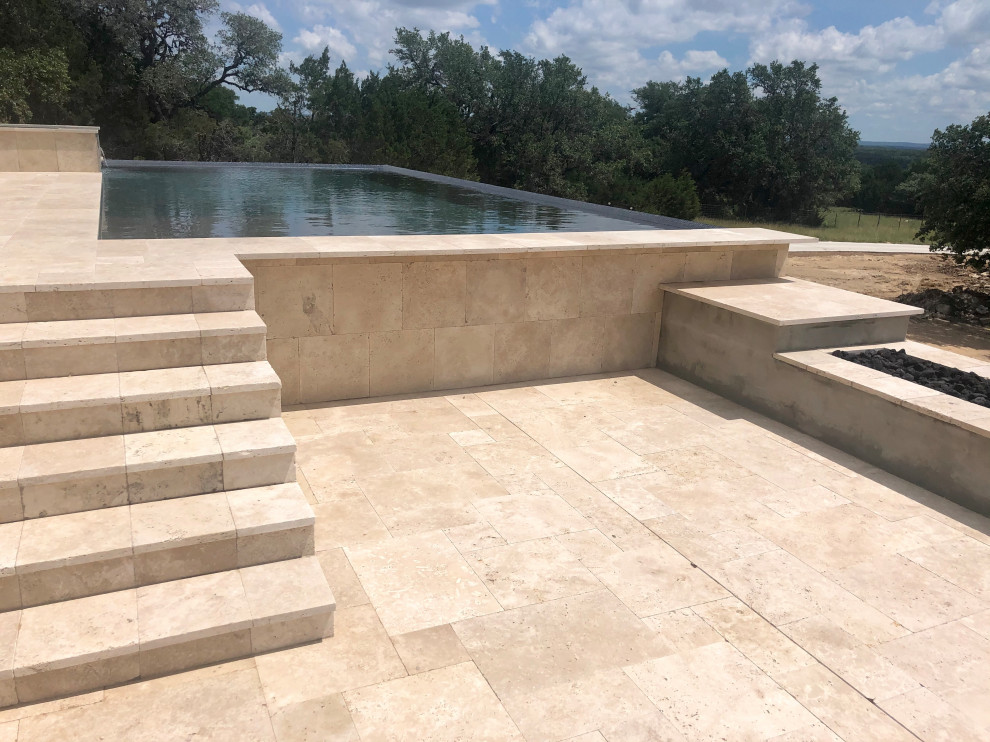 На фото: огромный прямоугольный бассейн-инфинити на заднем дворе в стиле модернизм с джакузи и покрытием из каменной брусчатки
