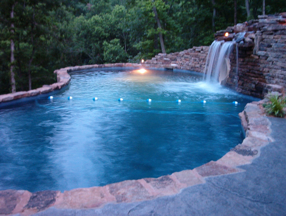 Foto de piscina con fuente natural rústica grande a medida en patio trasero con suelo de hormigón estampado