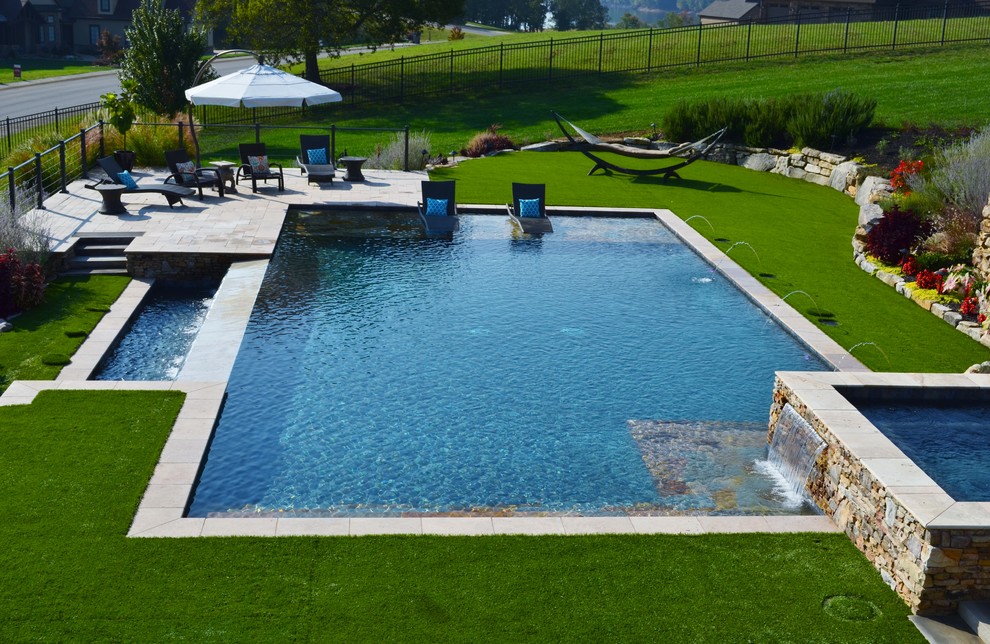 Modelo de piscinas y jacuzzis alargados contemporáneos grandes rectangulares en patio trasero con adoquines de piedra natural
