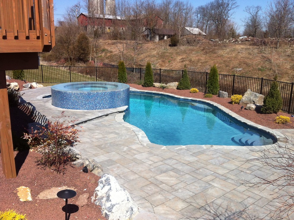 Esempio di una piscina naturale stile rurale personalizzata di medie dimensioni e dietro casa con pavimentazioni in cemento
