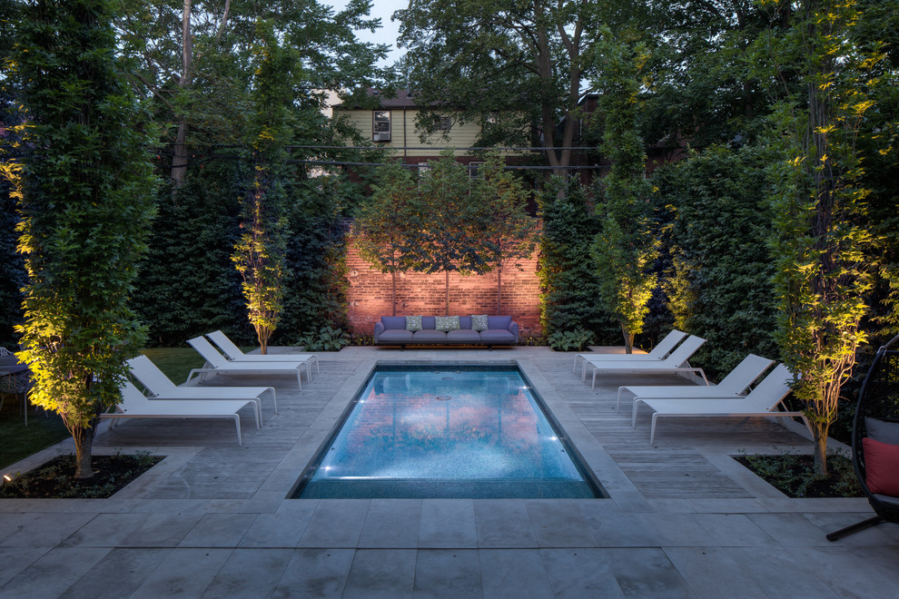 Foto de piscina actual pequeña rectangular en patio trasero con adoquines de piedra natural