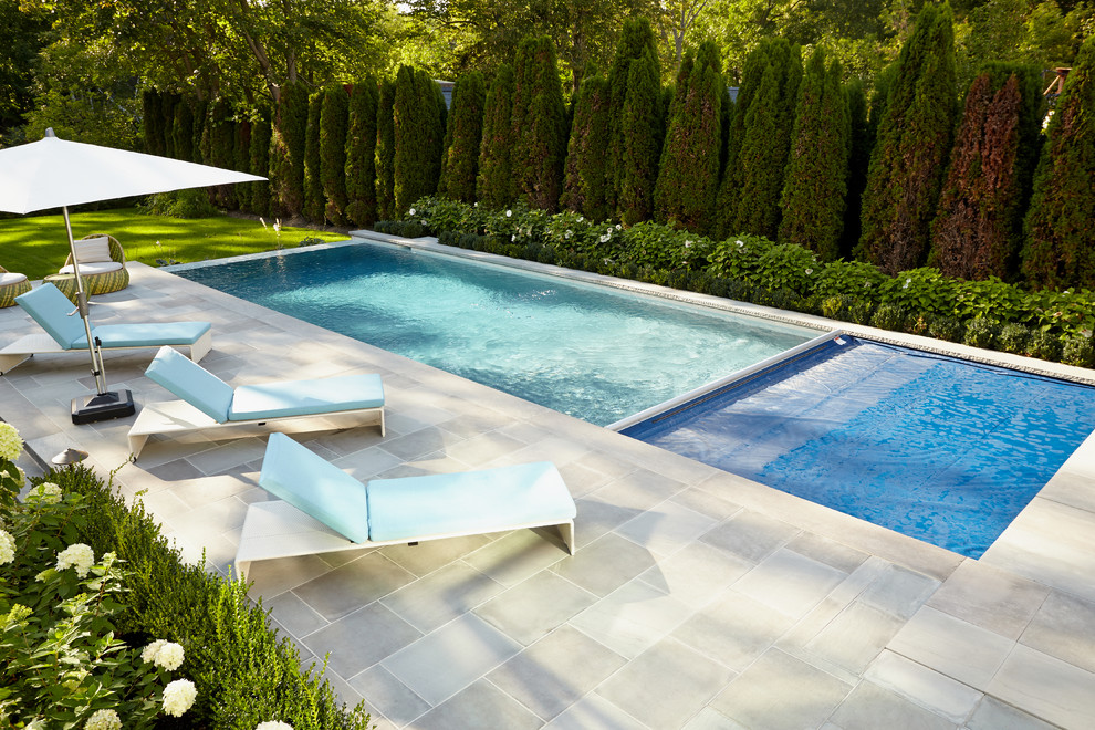 Modelo de piscina con fuente infinita clásica renovada grande rectangular en patio trasero con adoquines de piedra natural