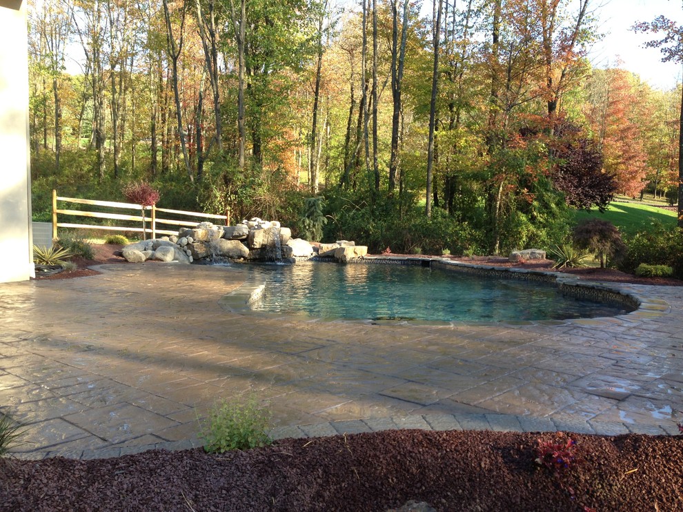 Diseño de piscina con fuente natural rural de tamaño medio a medida en patio lateral con adoquines de hormigón