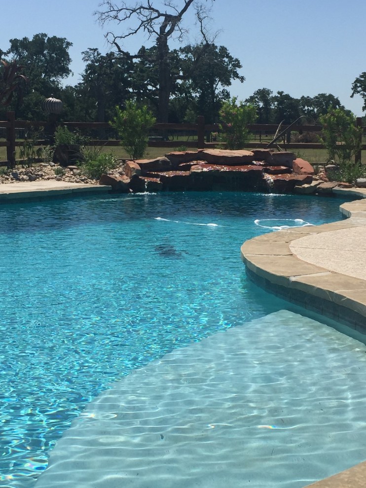 Example of a mid-sized minimalist backyard custom-shaped natural pool fountain design in Houston with decking