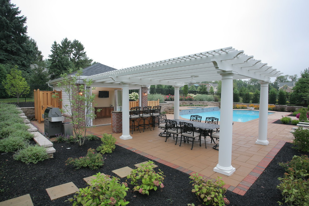 Imagen de casa de la piscina y piscina alargada tradicional grande rectangular en patio trasero con adoquines de hormigón