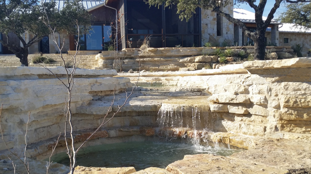 Großer Mediterraner Schwimmteich hinter dem Haus in individueller Form mit Wasserrutsche und Natursteinplatten in Austin