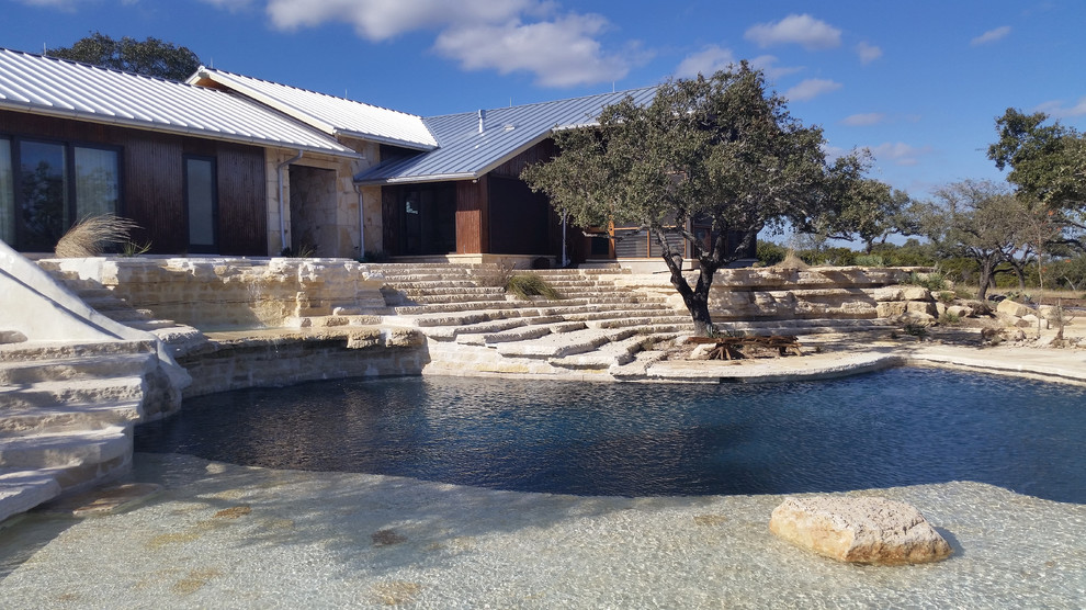 Ispirazione per una grande piscina naturale american style personalizzata dietro casa con un acquascivolo e pavimentazioni in pietra naturale