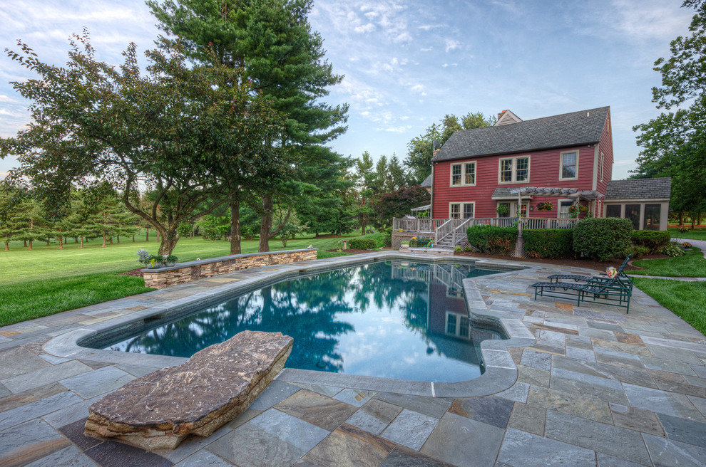 Immagine di una piscina naturale tradizionale personalizzata dietro casa con pavimentazioni in pietra naturale