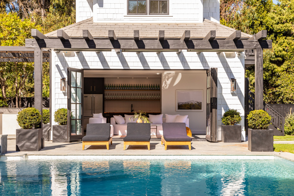 Diseño de casa de la piscina y piscina costera grande rectangular en patio trasero con adoquines de hormigón