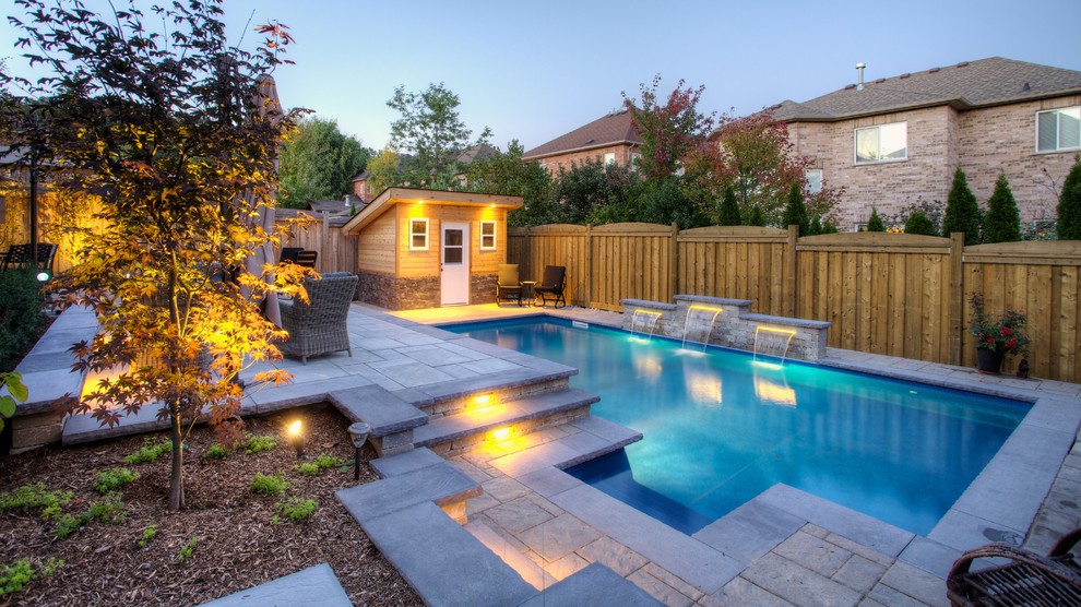 Foto di una piscina naturale contemporanea rettangolare di medie dimensioni e dietro casa con pavimentazioni in pietra naturale