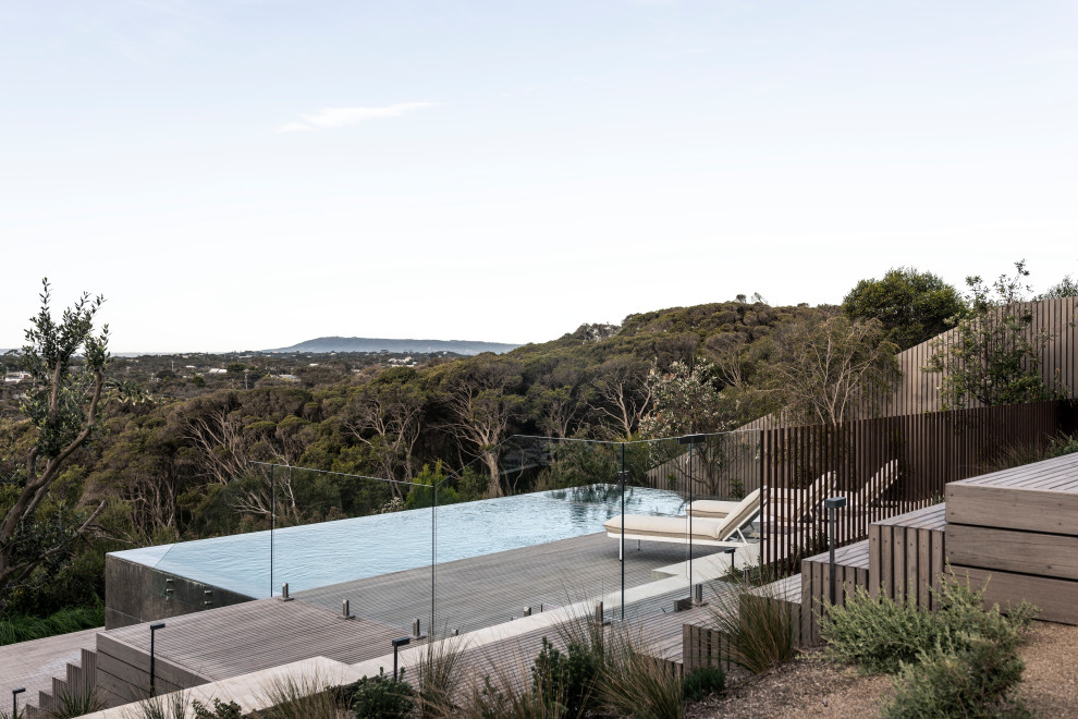 Großer Maritimer Infinity-Pool hinter dem Haus in rechteckiger Form mit Dielen in Sonstige