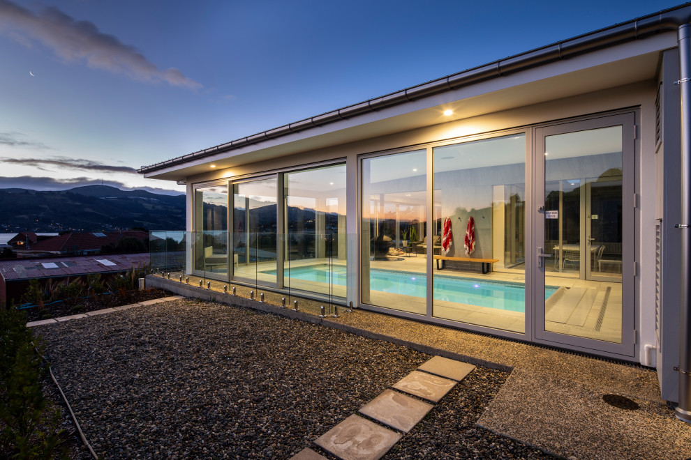 На фото: большой естественный, прямоугольный бассейн в доме в стиле модернизм с домиком у бассейна