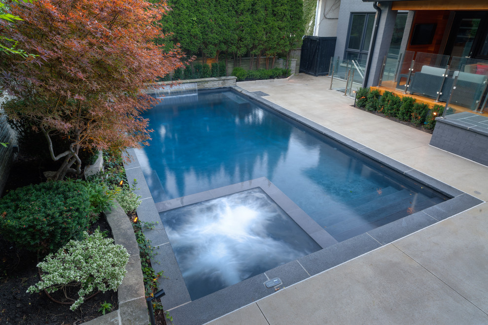 Großer Klassischer Pool hinter dem Haus in rechteckiger Form mit Wasserspiel in Sonstige