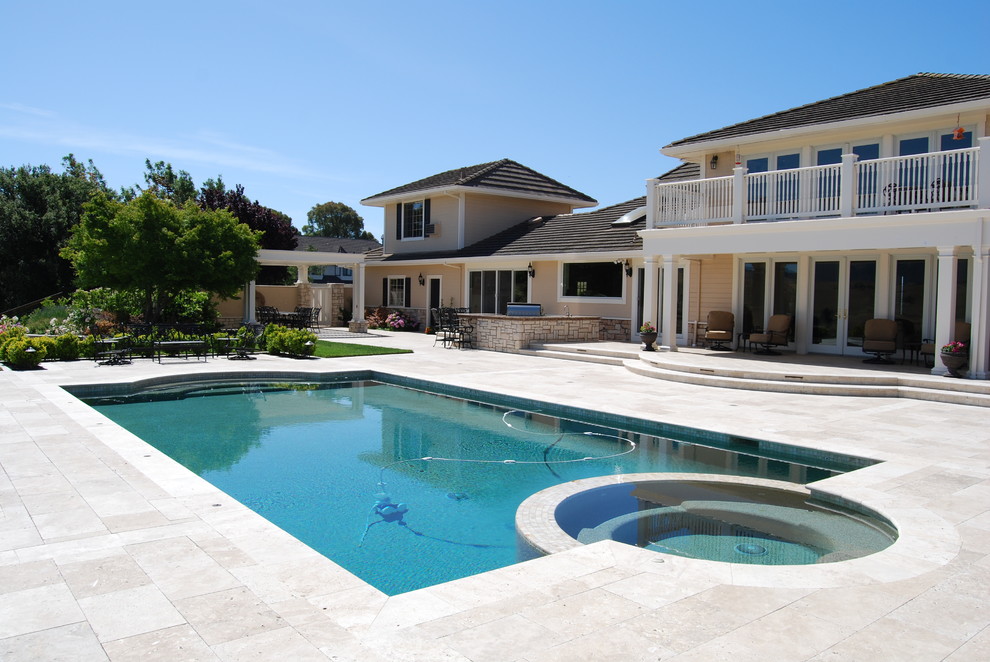 Ispirazione per un'ampia piscina mediterranea personalizzata dietro casa con una vasca idromassaggio e pavimentazioni in pietra naturale