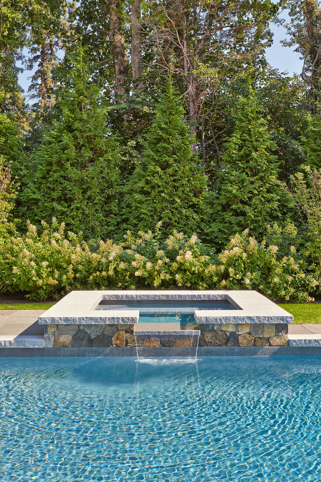 Idée de décoration pour une piscine latérale tradition de taille moyenne et rectangle avec un bain bouillonnant et des pavés en pierre naturelle.