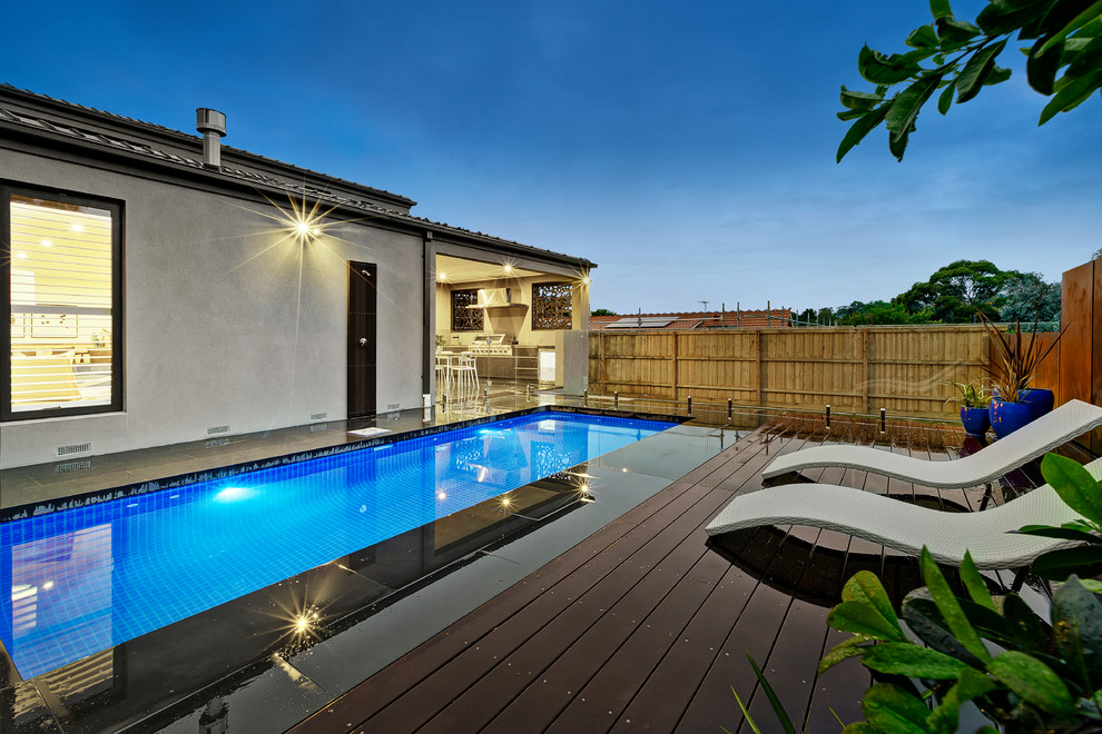 Aménagement d'un couloir de nage arrière contemporain de taille moyenne et rectangle avec une terrasse en bois.