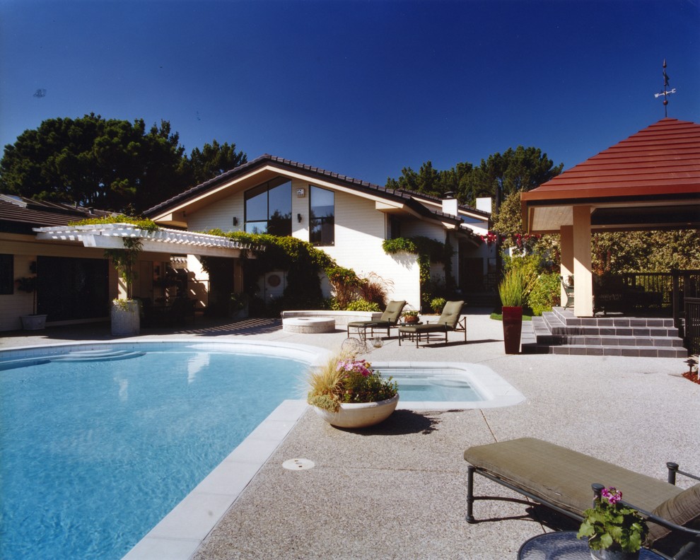 Foto de piscinas y jacuzzis alargados actuales grandes a medida en patio trasero con losas de hormigón