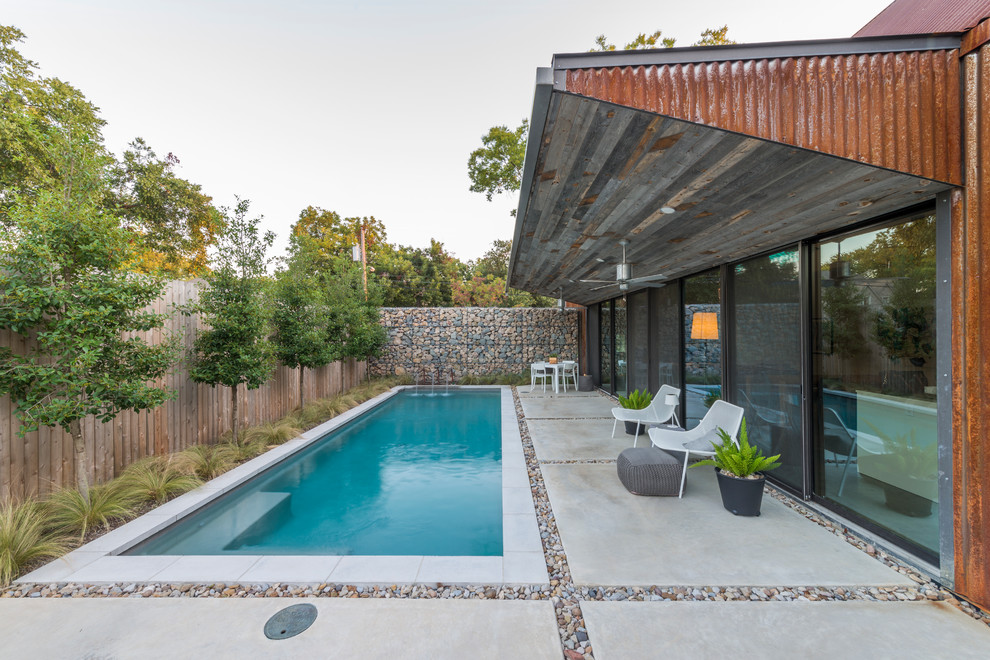 Ejemplo de piscina con fuente alargada urbana pequeña rectangular en patio trasero con adoquines de hormigón