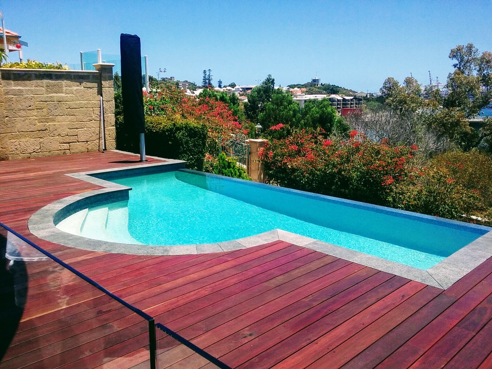 Design ideas for a medium sized modern back custom shaped infinity swimming pool in Perth with decking.