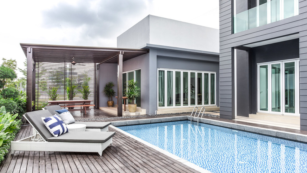 Modelo de piscina alargada actual de tamaño medio rectangular en patio trasero con entablado