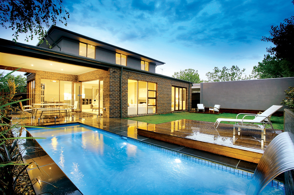 Стильный дизайн: спортивный, прямоугольный бассейн на заднем дворе в стиле модернизм с фонтаном и покрытием из каменной брусчатки - последний тренд
