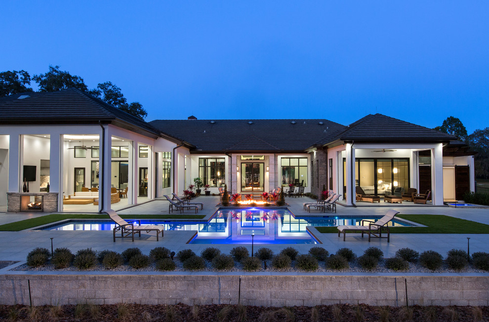 Diseño de piscina alargada contemporánea extra grande a medida en patio trasero con adoquines de hormigón