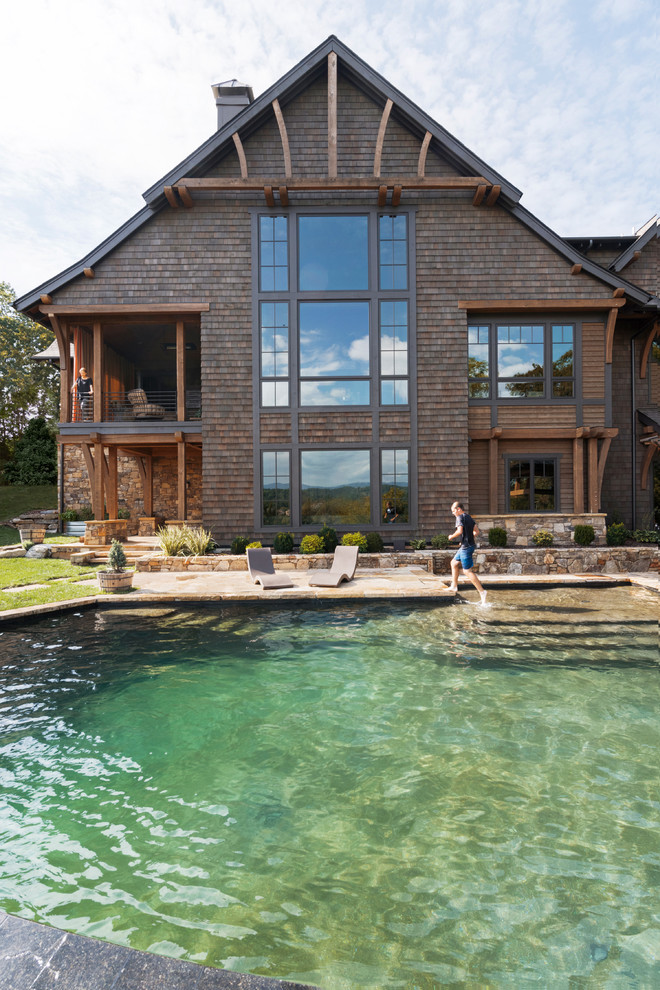 Ispirazione per una grande piscina a sfioro infinito rustica personalizzata dietro casa con pavimentazioni in pietra naturale
