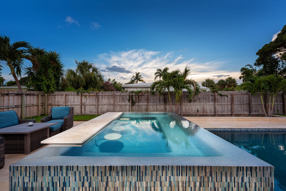 Foto de piscinas y jacuzzis infinitos minimalistas de tamaño medio a medida en patio trasero con adoquines de piedra natural