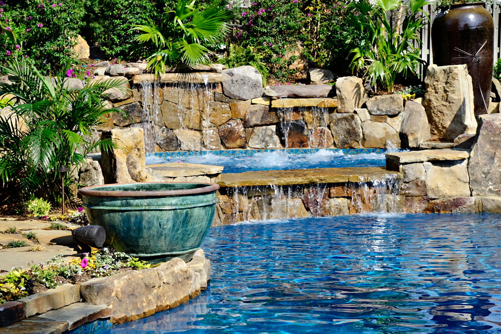 Exemple d'une piscine arrière exotique de taille moyenne et sur mesure avec un bain bouillonnant et des pavés en pierre naturelle.
