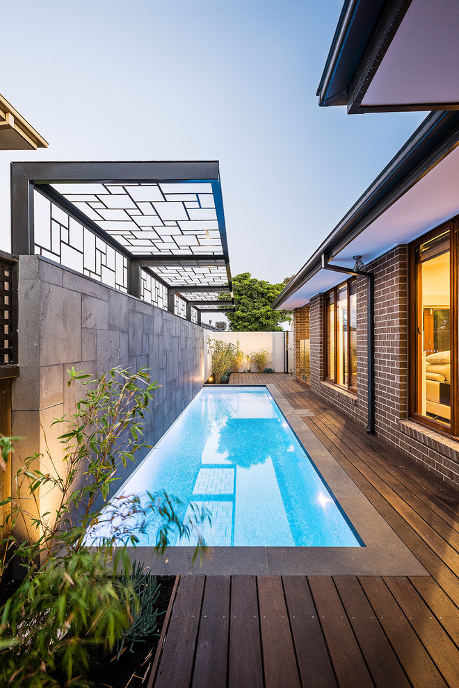 Ejemplo de piscina alargada actual pequeña rectangular en patio lateral con entablado