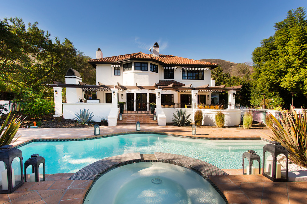 Foto di una grande piscina monocorsia mediterranea personalizzata dietro casa con una vasca idromassaggio e piastrelle