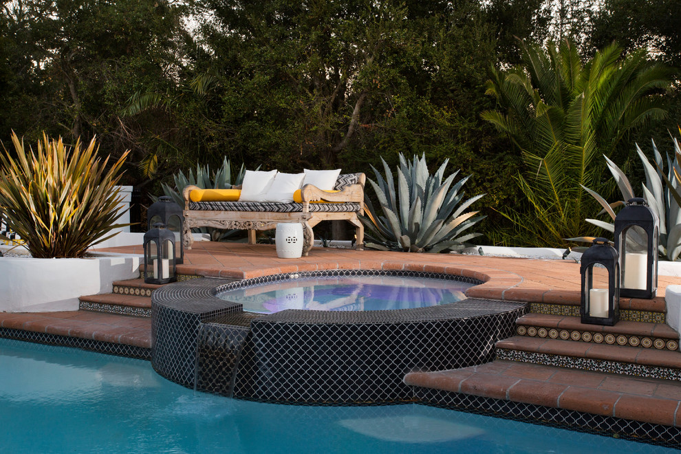 Immagine di una grande piscina naturale mediterranea personalizzata dietro casa con una vasca idromassaggio e piastrelle