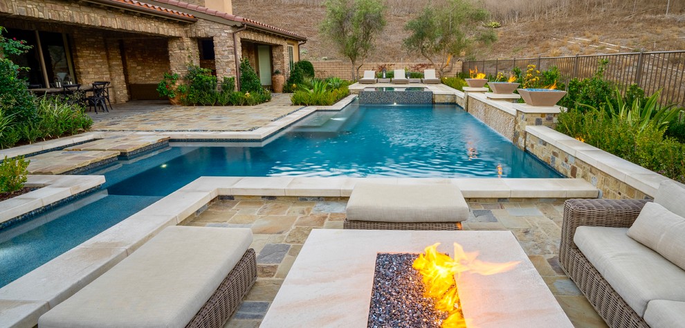 Modelo de piscina con fuente actual grande rectangular en patio trasero con adoquines de piedra natural