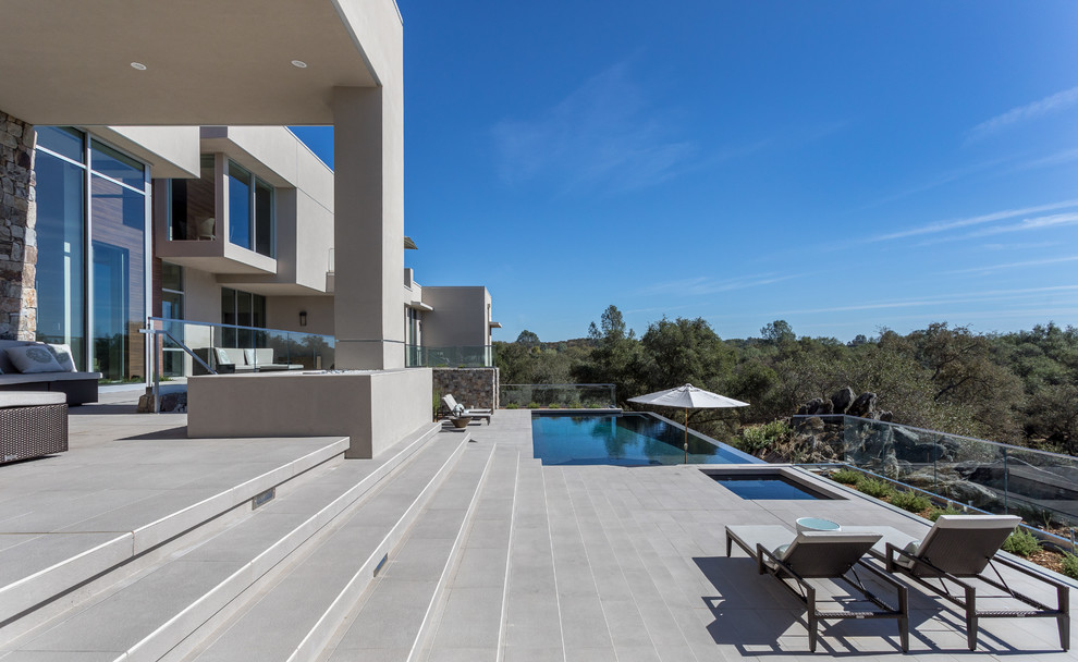Foto de piscinas y jacuzzis infinitos contemporáneos grandes rectangulares en patio trasero con losas de hormigón