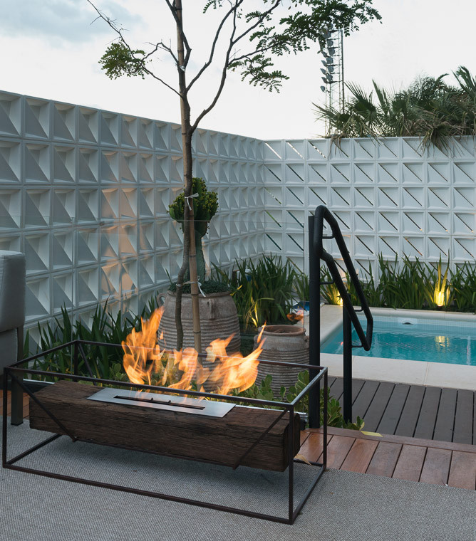 Imagen de piscina alargada tropical de tamaño medio rectangular en patio lateral con paisajismo de piscina y entablado