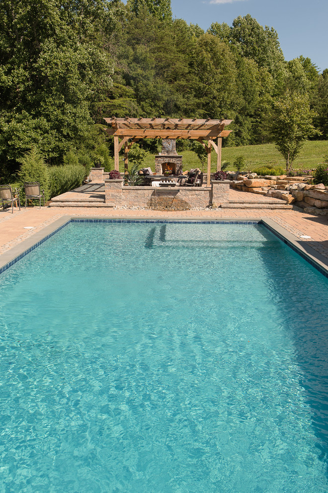 Ejemplo de piscina rural grande rectangular en patio trasero con adoquines de hormigón