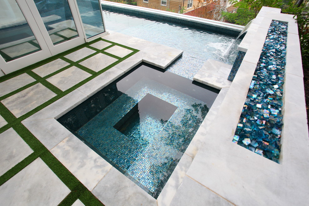 Idee per una grande piscina monocorsia minimalista a "L" dietro casa con fontane e lastre di cemento