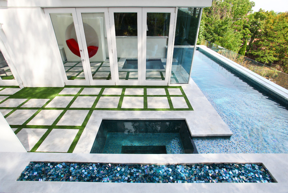 На фото: большой спортивный, угловой бассейн на боковом дворе в стиле модернизм с джакузи и покрытием из бетонных плит с