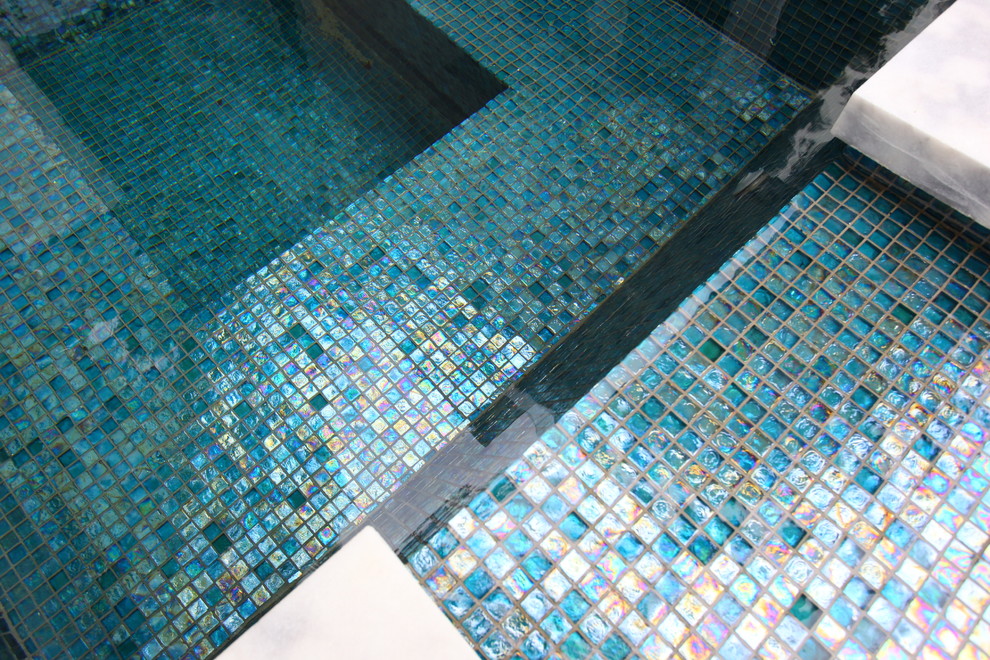 Foto di una grande piscina monocorsia moderna a "L" dietro casa con fontane e lastre di cemento
