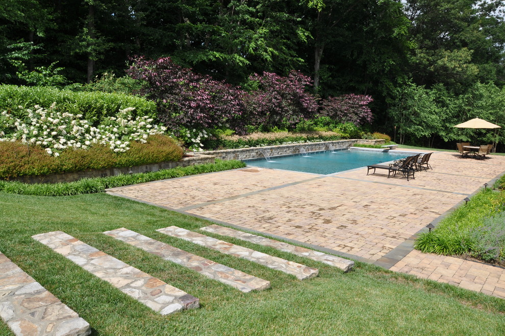 Exemple d'une piscine chic rectangle avec des pavés en pierre naturelle et un point d'eau.